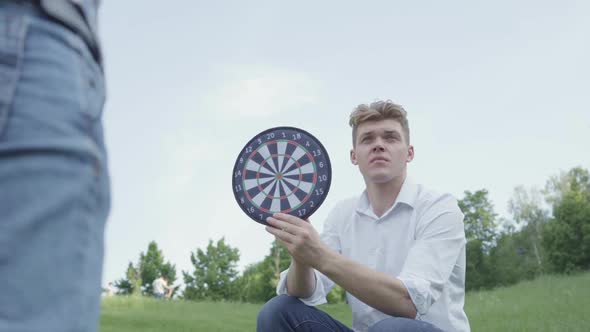 Cheerful Young Father Holding Darts While His Son Throwing Darts on a Magnet in the Circles. Family