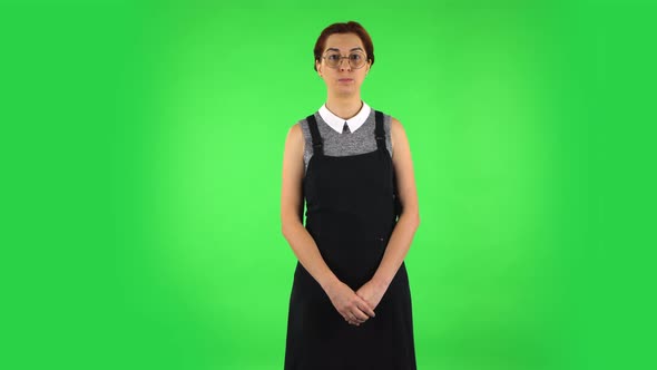 Funny Girl in Round Glasses Is Smiling While Looking at Camera. Green Screen