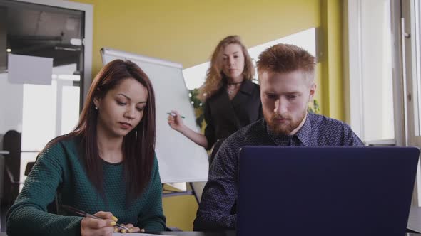 Young Man Is Looking at Laptop Screen, Sitting at Table in Office.