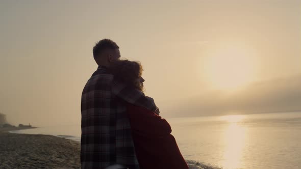 Romantic Woman and Man Standing on Beach at Sunrise