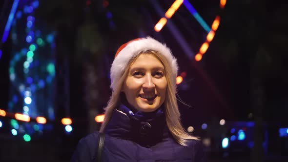 a woman chatting on her smartphone wearing a Santa hat is a night city.