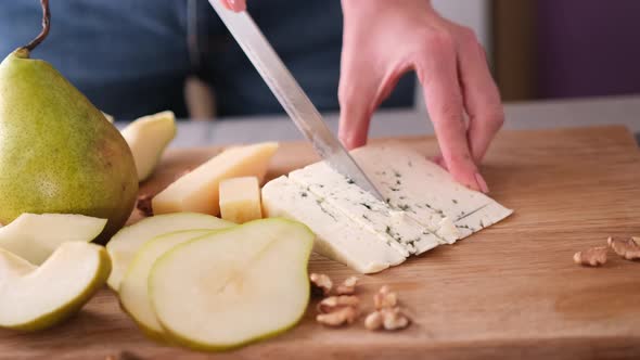 Making Pear and Blue Cheese Salad on  Slicing Cheese on a Wooden Board