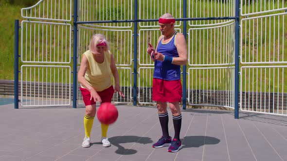 Senior Man Coach Teaching Grandmother with Basketball Dribbling Exercise with Ball on Playground