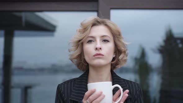 Pretty Girl Drinks a Cup of Tea at Home in Windy Day. Slowly