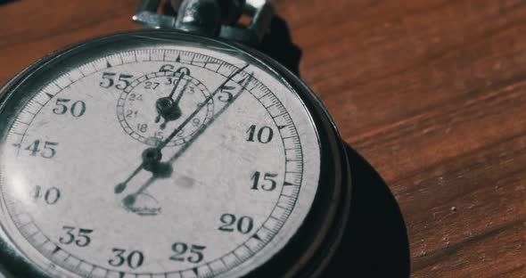 Old Vintage Stopwatch Lies on Wooden Table and Counts the Seconds