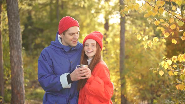 Attractive Couple Tourists Stands in Autumn Forest with Cup of Tea and Admires the Beautiful View