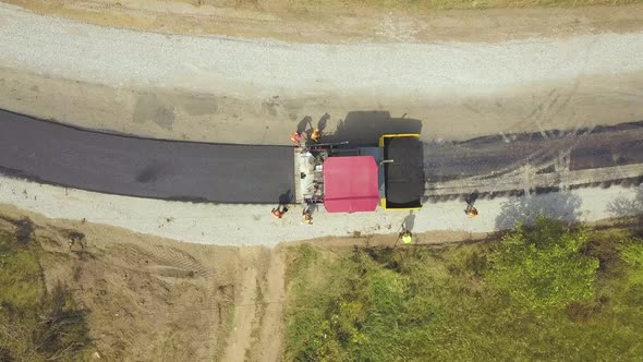 Aerial View of New Road Construction with Workers and Asphalt Laying Machinery at Work