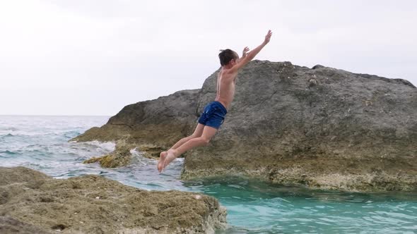 Kid diving into sea from rock.