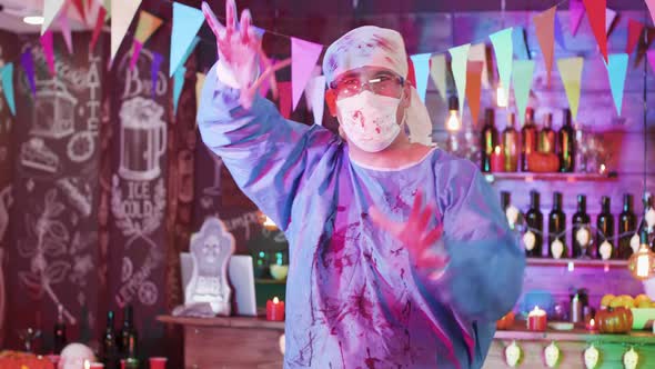 Scary Blood-stained Mad Surgeon Costume in a Halloween Decorated Bar Before a Party