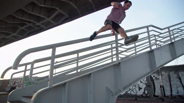 the Parkour Rider Jumping Down the Stairs Against the Background of Cement Walls Covered with