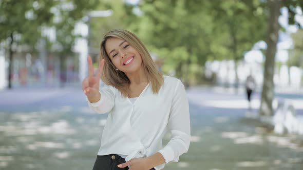 Cheerful Young Woman Showing Victory Sign