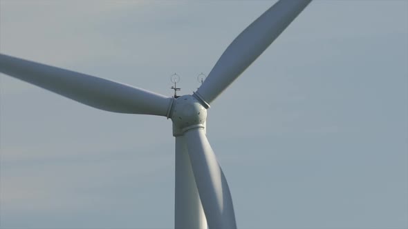 Motion the Blades of a Large Wind Turbine in a Field Against a Background of Orange Sunset on the