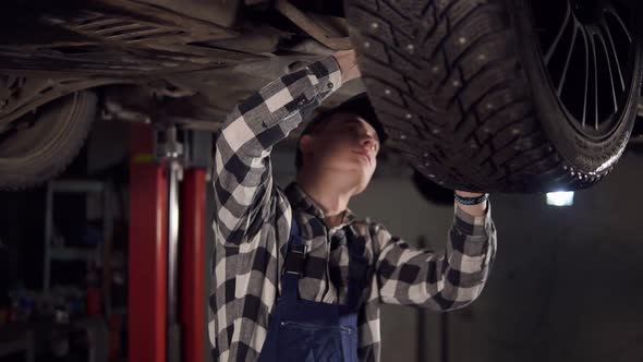 Handsome Mechanic Reparing a Car Fromthe Bottom in His Workshop