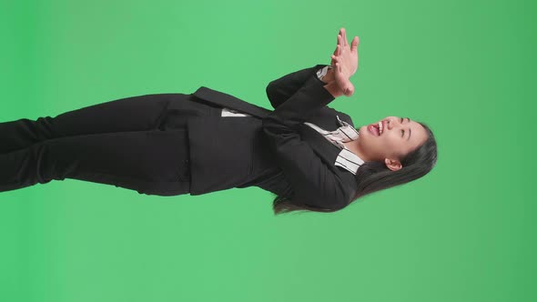 Side View Of An Asian Business Woman Blowing Kisses And Smiling In The Green Screen Studio