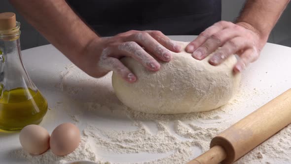 Male Hands Kneading Dough with Flour on Kitchen Table