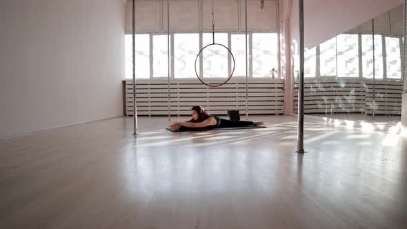 A Young Woman Sitting in a Splits on the Floor and Stretching