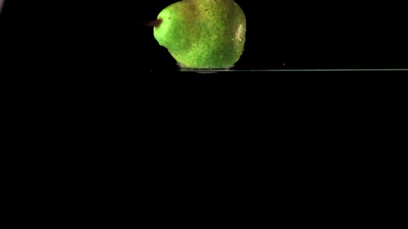 Super Slow Motion One Green Pear Falls Under the Water with Air Bubbles