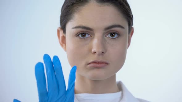 Female Doctor Wearing Surgical Mask, Looking Into Camera as if Examining Patient