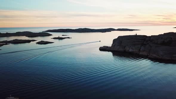 Drone flying towards motorboat over open waters during sunset.