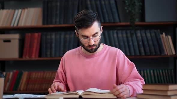 Confident Smart Hispanic Man Reading Vintage Paper Book Turning Pages at Public Library Desk