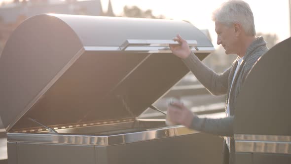 Portrait of Aged Man Throwing Paper Cup in Litter Bin Outdoors