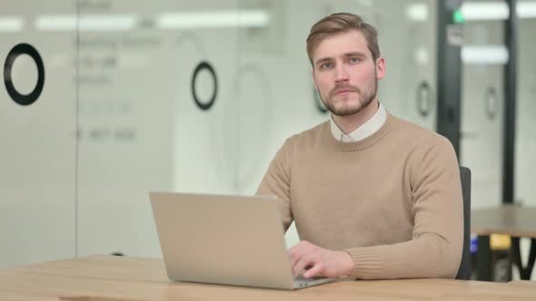 Creative Young Man with Laptop Looking at the Camera