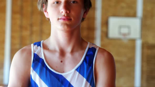 Portrait of schoolboy standing in basketball court