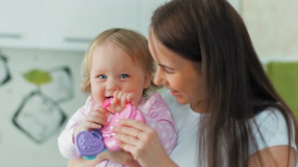 Happy Mother and Her Little Cheerful Daughter Playing at Home