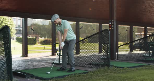 Young Man Playing Golf at Club, Hitting Ball at Individual Training Course