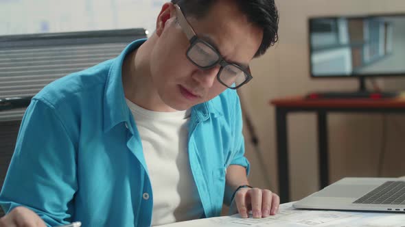 Close Up Of Asian Man Engineer With A Laptop Drawing Blueprint At The Office