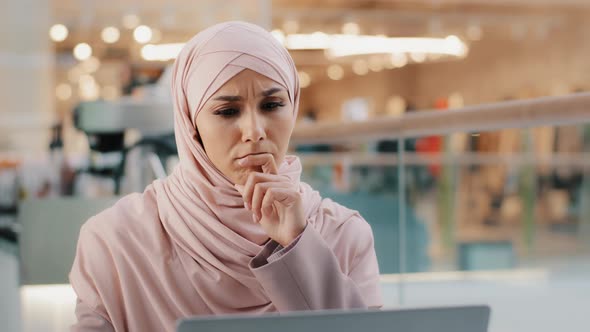 Young Pensive Puzzled Arab Woman in Hijab Working on Laptop Concentrating on Idea Looking for