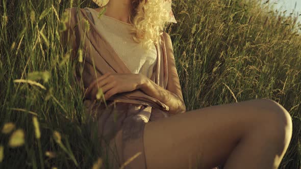 Young Girl Sitting in the Grass and Posing at the Camera