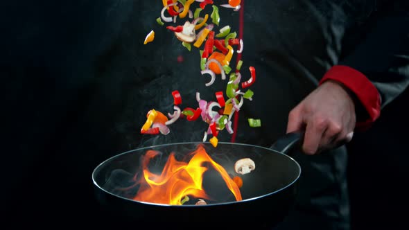 Super Slow Motion Shot of Chef Holding Frying Pan and Falling Vegetables Into Fire at 1000Fps