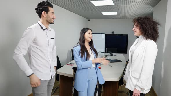 Portrait of Excited Asian Woman Talking with Positive Multiethnic Colleagues Standing