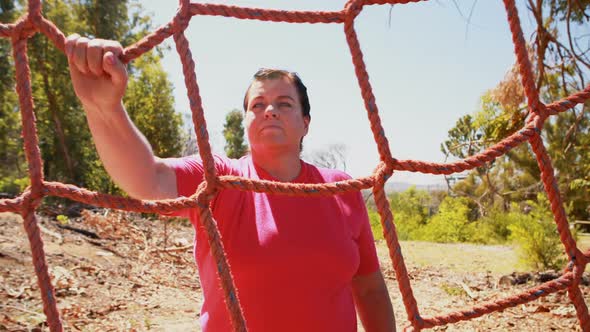 Determined woman climbing a net during obstacle course