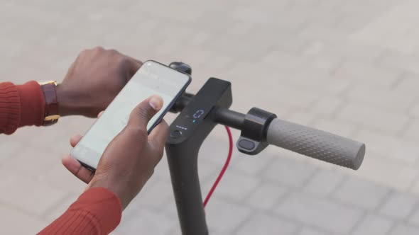 Man Activating E-Scooter with App on Smartphone