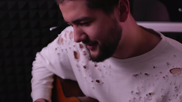 Handsome Man Plays Guitar and Sings Into Microphone in Recording Studio