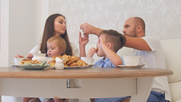 Happy Young Family Enjoying Tea with Sweets at Restaurant