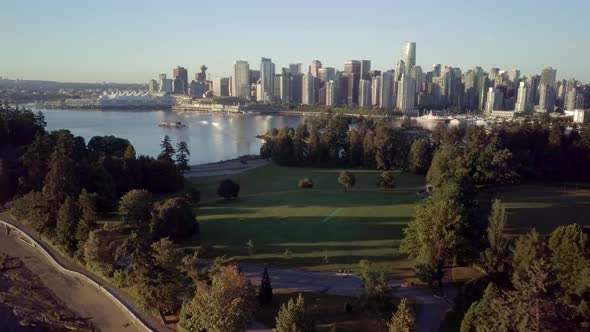 The Lush Green Trees At Brockton Point Of Stanley Park Overlooking The Downtown Skyline Of Vancouver