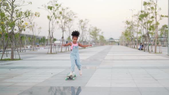 4K Little African girl practicing longboard sakting at the park on summer vacation