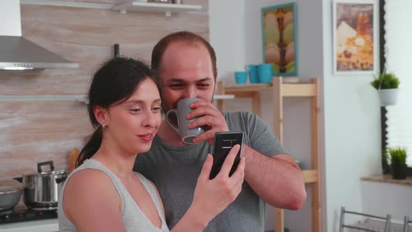 Authentic Couple in the Morning Smiling and Looking at Phone