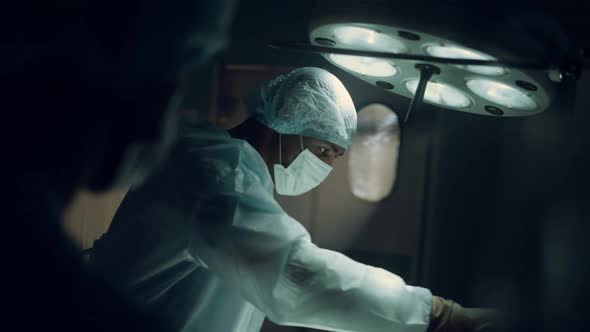 Focused Surgeon Performing Operation in Dark Sterile Hospital Operating Room