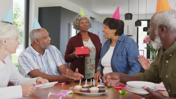 Happy senior diverse people at birthday party with cake and gifts at retirement home