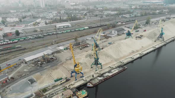 Sand Iron industrial barge with sand floating near cargo working cranes. Sand Extraction