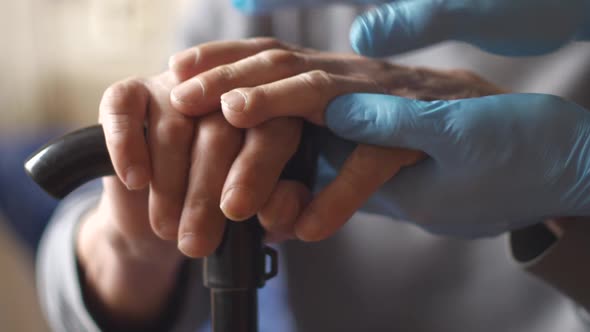 Close-up of the hands of a senior citizen holding a walking stick, The hands of a medic in gloves sh