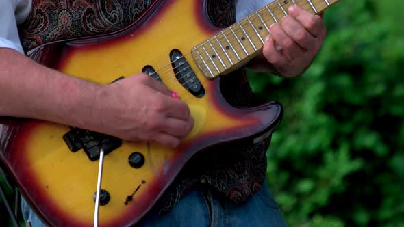 Man Playing Old Guitar Using Mediator Outdoor