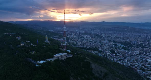 Aerial view of center of Tbilisi under Mtatsminda mountain at sunset. Georgia 2022 summer