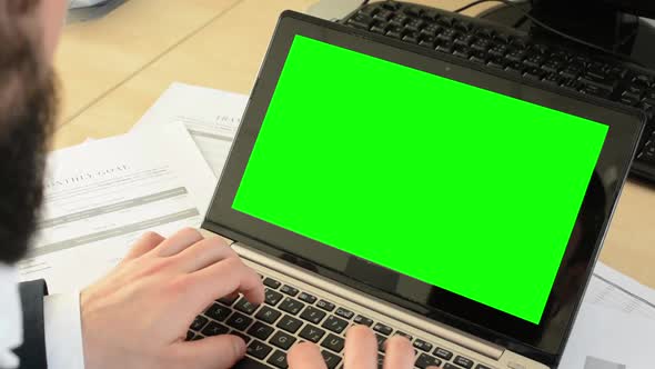 Young Handsome Man with Full-beard (Hipster) Works on Laptop in the Office - Computer