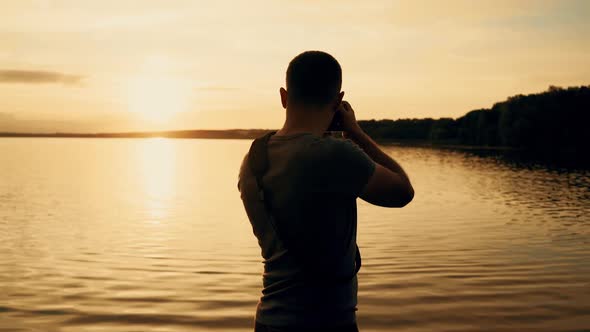Photographer silhouette at sunrise. Beautiful summer sunset by the river