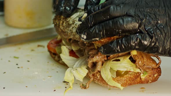 Close up of hands preparing roast beef sandwich